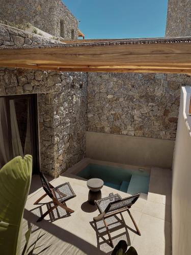 a patio with two chairs and a swimming pool at Anemelia Hotel Mykonos in Elia Beach