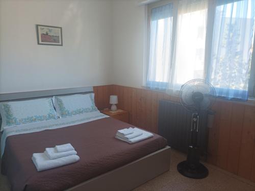 a bedroom with a bed with towels and a fan at Affitta camere Via Piave in Foligno