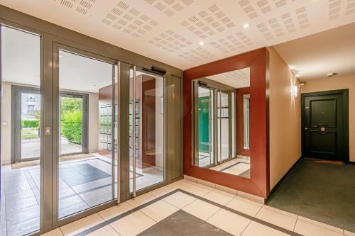 un couloir avec des portes coulissantes en verre et une porte noire dans l'établissement Sweet cocon à Disney, à Montévrain