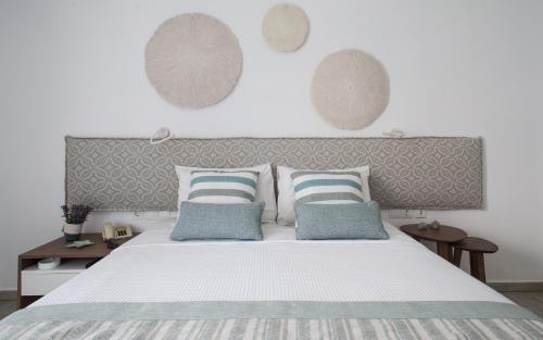 a bedroom with a large white bed with blue pillows at Aurora - Rooms & Suites - Spetses in Spetses