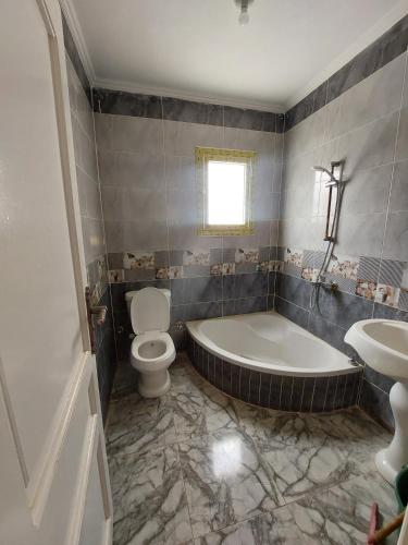 a bathroom with a tub and a toilet and a sink at شاليه سوبر لوكس in El Alamein