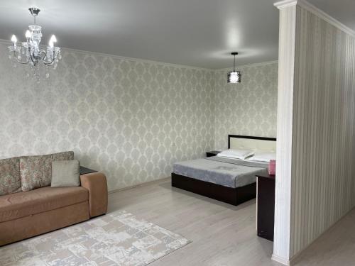 a bedroom with a bed and a couch at Уютная квартира-студия в Атырау ЖК MODERN SITY in Atyraū