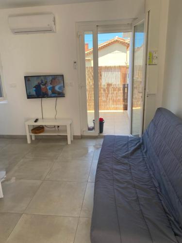 - un salon avec un lit et une porte coulissante en verre dans l'établissement Appartement T2 Valras plage 400m de la plage, à Valras-Plage