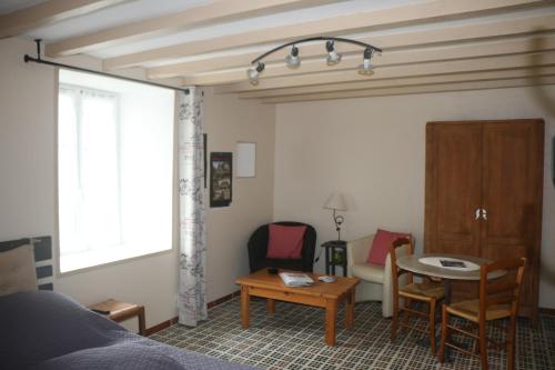 une chambre avec un lit, une table et des chaises dans l'établissement Le petite écurie, à Saint-Georges-de-Bohon