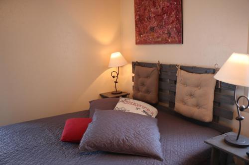 - une chambre avec un lit avec un oreiller et deux lampes dans l'établissement Le petite écurie, à Saint-Georges-de-Bohon