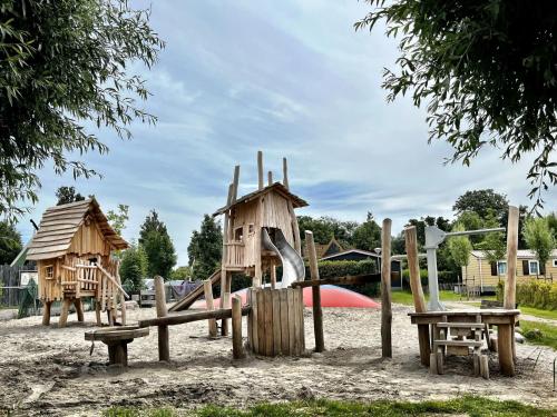 a playground with wooden play equipment in a park at Holiday Home Wiringherlant-2 by Interhome in Noordstroe