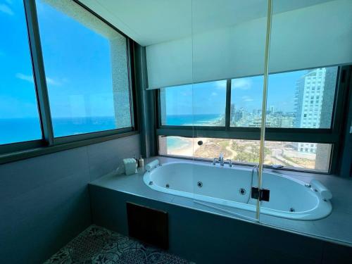 a bath tub in a bathroom with large windows at C Tower Premium Apartments, Panoramic Sea View in Netanya
