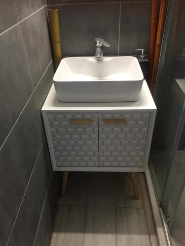 une salle de bain avec un lavabo blanc sur un meuble dans l'établissement Un jardin près de la plage, à Hyères