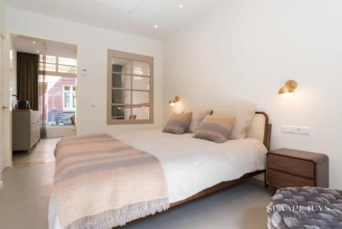 a white bedroom with a large bed with pillows at Slaaphuys Bed & Sauna in Alkmaar