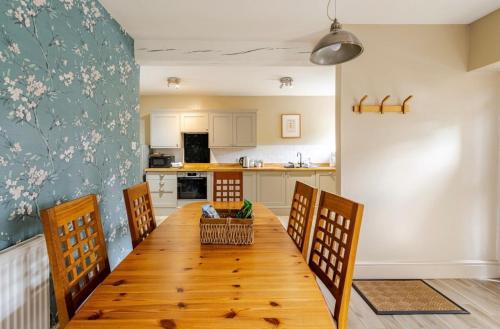 a dining room table with chairs and a kitchen at The Stables in Stoney Middleton
