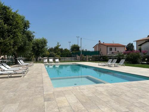 a large swimming pool with lounge chairs at Ca' Barbieri San Donà in San Donà di Piave