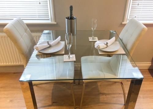 a glass table with white chairs and napkins on it at Luxury Apartment with King-size Bed in Central Cambridge - Walk to Station and City Centre in Cambridge