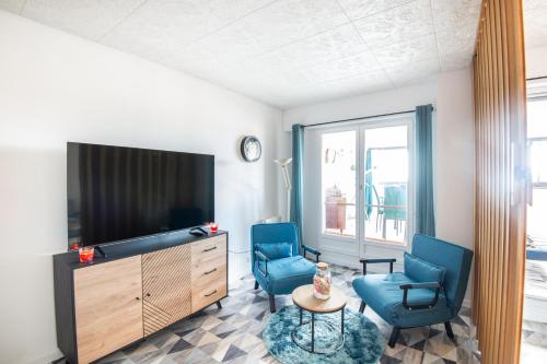 un salon avec deux chaises bleues et une télévision dans l'établissement Titi - À Courseulles-sur-Mer, 7 min de la plage, à Courseulles-sur-Mer