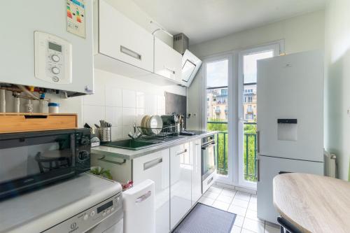 une cuisine avec des appareils blancs et une grande fenêtre dans l'établissement Bleu en Bois - À Chessy à 10 min de Disneyland, à Chessy