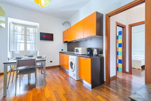 a kitchen with orange cabinets and a table and a microwave at Residenza Duomo in Alba