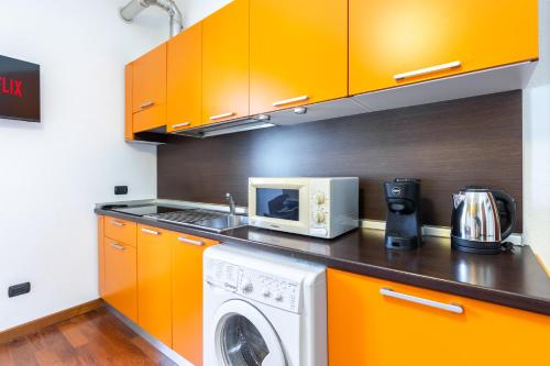 a kitchen with orange cabinets and a washing machine at Residenza Duomo in Alba