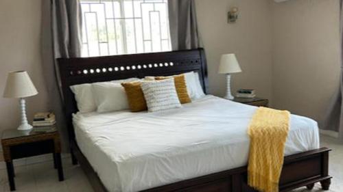 a bedroom with a large bed with two lamps and a window at ZenBreak Hope Winds in Christ Church