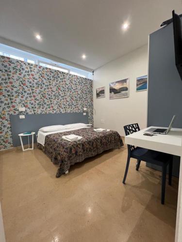 a bedroom with a bed and a desk with a laptop at BURMARIA APARTMENT and ROOM with garden and jacuzzi in Tropea