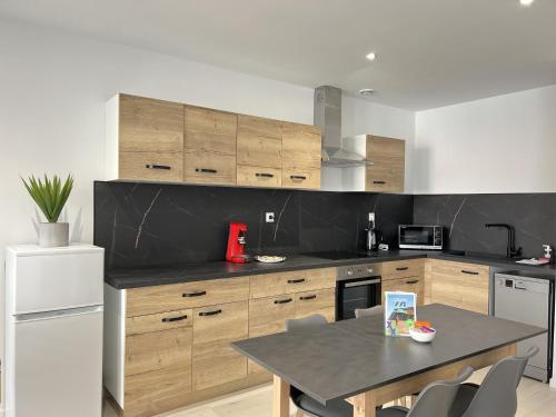 une cuisine avec des armoires en bois et une table avec des chaises dans l'établissement Le JP, à Calais