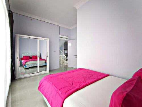 a bedroom with a large pink bed and a mirror at Villa Tiara 2 in Cikundul