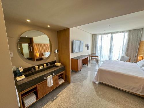 a bedroom with a bed and a bathroom with a mirror at Hotel Mio Riviera Nayarit - Adults Only in Nuevo Vallarta 