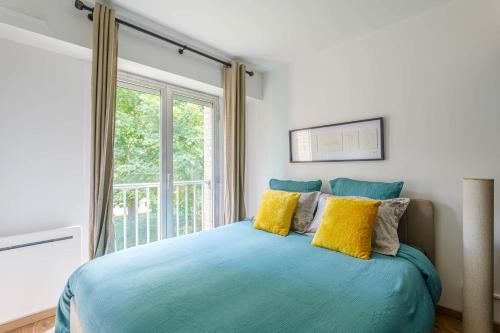 - une chambre avec un lit bleu et des oreillers jaunes dans l'établissement Appartement Croisé Laroche - 5 min de Lille, à Marcq-en-Barœul