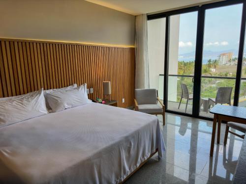 a bedroom with a white bed and a large window at Hotel Mio Riviera Nayarit - Adults Only in Nuevo Vallarta 