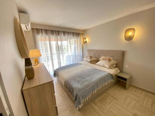 une chambre avec un lit et une grande fenêtre dans l'établissement Joli appartement prés de la mer, à Cannes