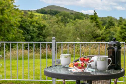 a table with two cups of coffee and fruit on it at Plas Drygarn Ty Gwyrdd Crymych in Crymych