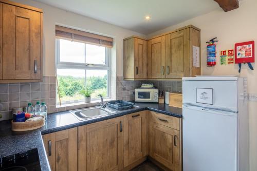 a kitchen with wooden cabinets and a white refrigerator at Plas Drygarn Ty Gwyrdd Crymych in Crymych