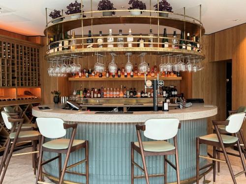 a bar in a restaurant with chairs and a chandelier at Lucknam Park Hotel in Chippenham