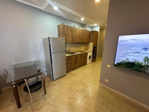 eine Küche mit Kühlschrank, Tisch und Fernseher in der Unterkunft Bakva's apartment in Batumi
