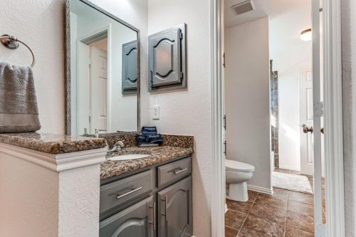 a bathroom with a sink and a toilet and a mirror at 5br Lux! Pool, Games & Theater in Rowlett