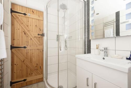 a bathroom with a shower and a glass door at Oriel Cottage in St. Agnes
