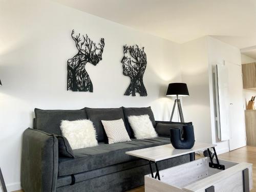 a living room with a couch and two pictures on the wall at Val d'Europe By Plaza - Proche Disneyland in Serris