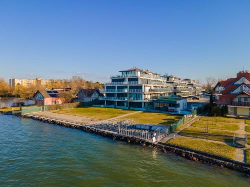 a large building next to a river with houses at LelleMarine by BLTN Apartmanok Balatonlelle in Balatonlelle