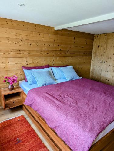 a bed in a room with a wooden wall at Swiss Mountain-Valley View Lodge in Erlenbach im Simmental
