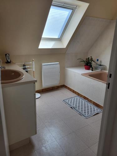 La salle de bains est pourvue de deux lavabos et d'une lucarne. dans l'établissement Maison Pays Fouesnantais