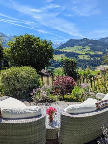 two wicker chairs sitting on a patio overlooking a valley at Swiss Mountain-Valley View Lodge in Erlenbach im Simmental