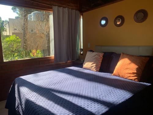 a bedroom with a blue and white bed with a window at Kimbara Bosque y Mar in Mar de las Pampas