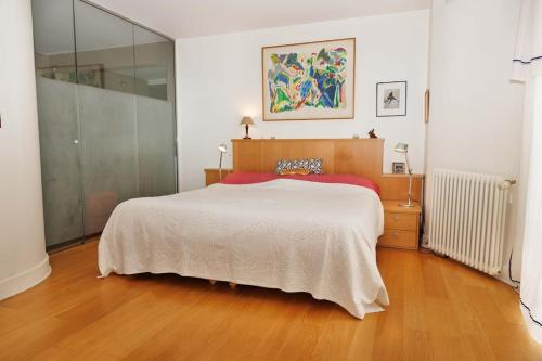 une chambre avec un grand lit et un parquet dans l'établissement Charmante maison - Boulogne, à Boulogne-Billancourt
