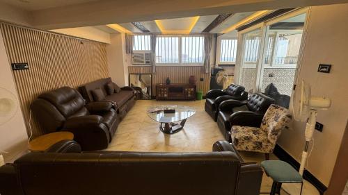 a living room with leather couches and a table at Riverfront Penthouse Studio with Spacious Terrace in Lucknow