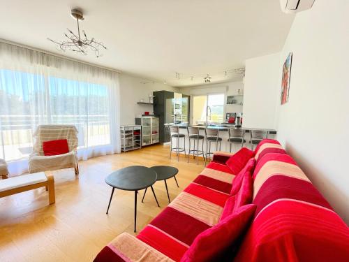 un salon avec un canapé rouge et une cuisine dans l'établissement PGH N8 - 100m de la Plage, Terrasse, Parking, à La Grande Motte