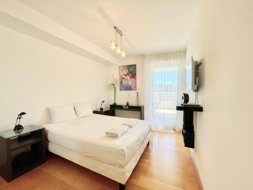 une chambre avec un grand lit blanc et une fenêtre dans l'établissement PGH N8 - 100m de la Plage, Terrasse, Parking, à La Grande Motte