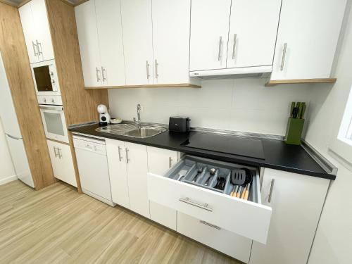 a kitchen with white cabinets and a sink at Apartamentos Zaragoza Gran Vía 3000 in Zaragoza