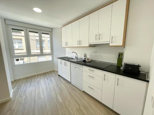 a kitchen with white cabinets and a wooden floor at Apartamentos Zaragoza Gran Vía 3000 in Zaragoza