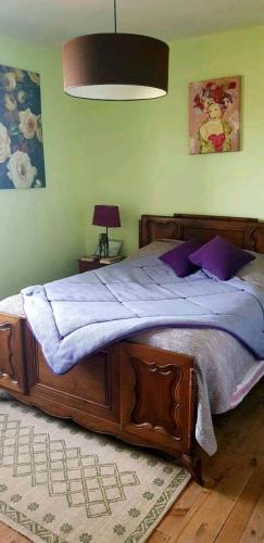 - une chambre avec un grand lit en bois et des oreillers violets dans l'établissement Gîte la Muzardie, à Campagne