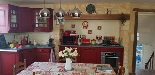 - une cuisine avec des placards rouges et une table fleurie dans l'établissement Gîte la Muzardie, à Campagne