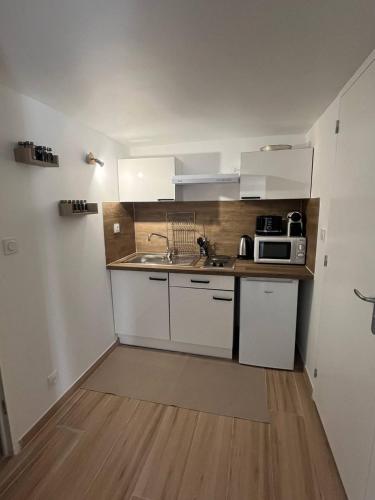 une petite cuisine avec un évier et un micro-ondes dans l'établissement Charmant et Confortable appartement Narbonne, à Narbonne