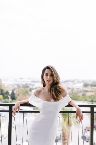 a woman in a white dress standing on a balcony at Legacy Gastro Suites in Heraklio Town